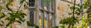 The gothic windows of Branford peek through tree branches 